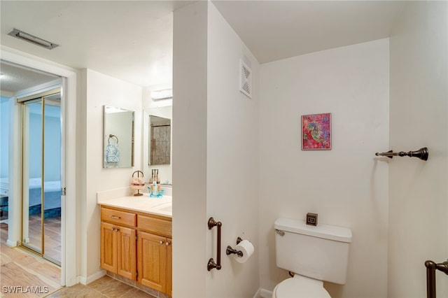 bathroom with toilet, visible vents, and vanity