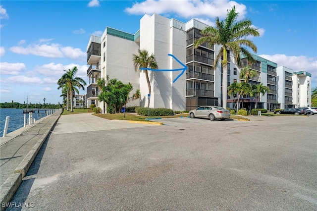 view of building exterior featuring uncovered parking and a water view