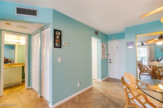 interior space featuring light tile patterned floors, baseboards, visible vents, and a ceiling fan