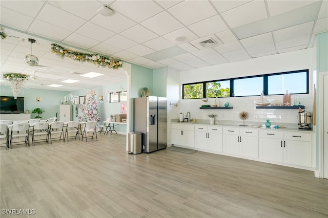 kitchen with visible vents, tasteful backsplash, white cabinets, and stainless steel fridge with ice dispenser