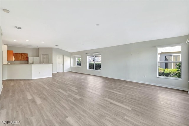 unfurnished living room with light wood-type flooring and lofted ceiling