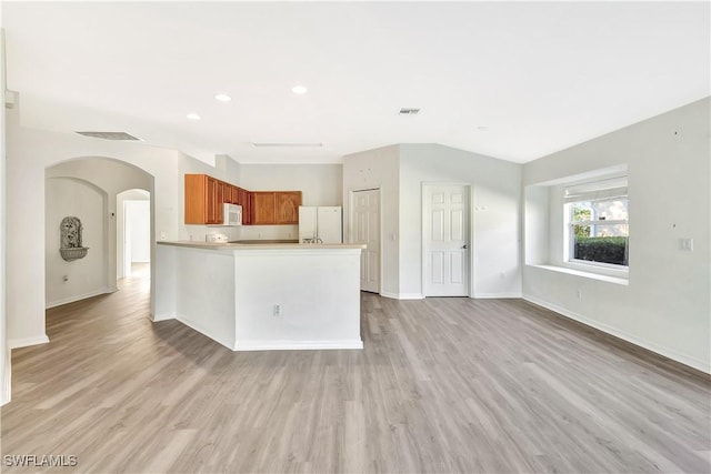 kitchen featuring kitchen peninsula, light hardwood / wood-style floors, and white appliances