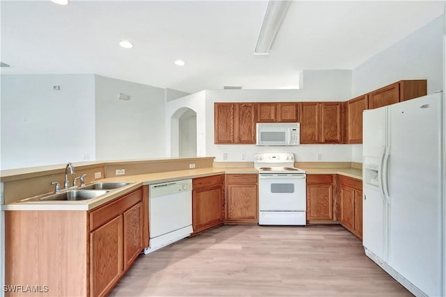 kitchen with kitchen peninsula, sink, white appliances, and light hardwood / wood-style flooring