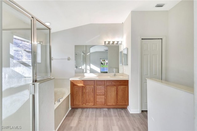 bathroom featuring vaulted ceiling, vanity, shower with separate bathtub, and hardwood / wood-style flooring