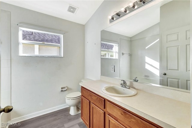 bathroom featuring hardwood / wood-style floors, vanity, toilet, and vaulted ceiling