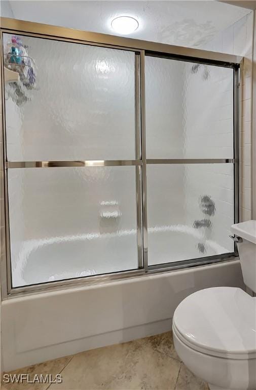 bathroom featuring bath / shower combo with glass door and toilet