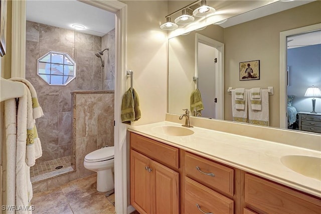 bathroom featuring tile patterned floors, vanity, toilet, and tiled shower