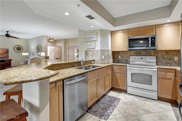 kitchen featuring ceiling fan, sink, kitchen peninsula, a kitchen bar, and appliances with stainless steel finishes