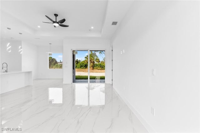 unfurnished room with ceiling fan, sink, and a tray ceiling