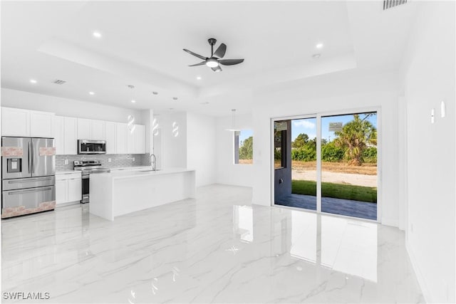 kitchen featuring white cabinets, a raised ceiling, sink, decorative light fixtures, and stainless steel appliances