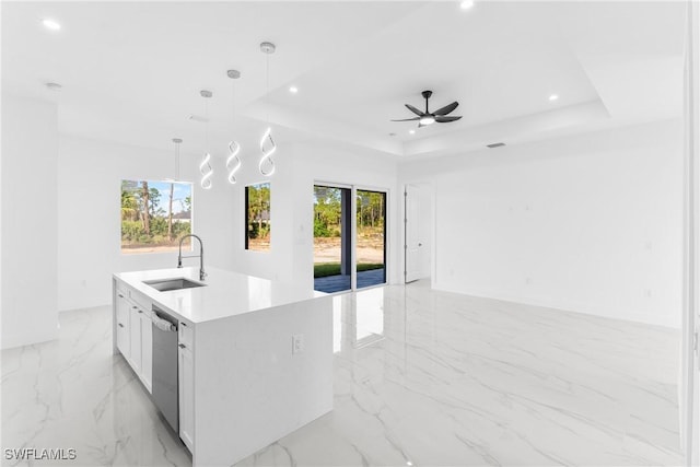 kitchen with sink, a raised ceiling, decorative light fixtures, a center island with sink, and white cabinets