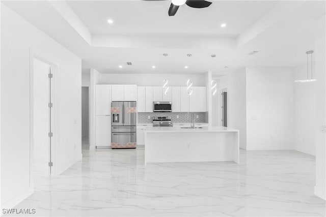 kitchen featuring appliances with stainless steel finishes, a kitchen island with sink, sink, decorative light fixtures, and white cabinetry