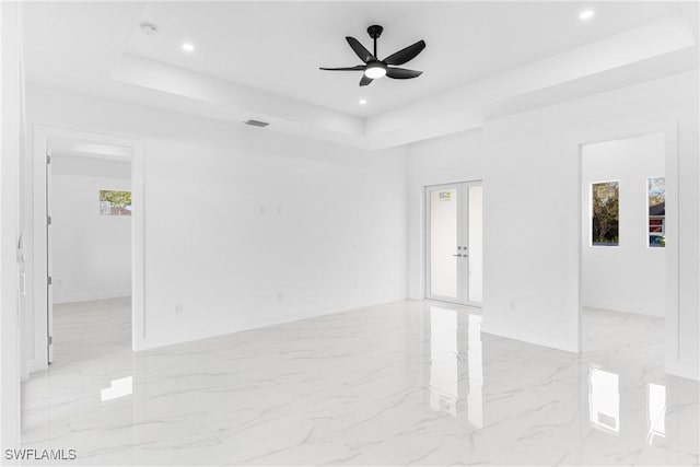 unfurnished room with french doors, a raised ceiling, and ceiling fan