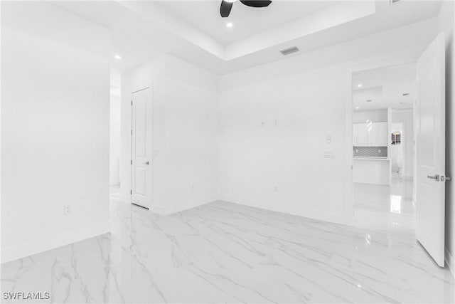 spare room featuring ceiling fan and a raised ceiling