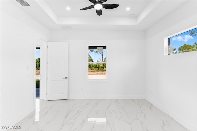 spare room featuring a tray ceiling and ceiling fan