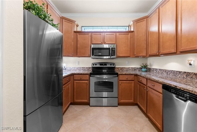 kitchen featuring crown molding, light tile patterned floors, stainless steel appliances, and dark stone counters