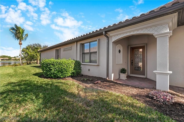 doorway to property with a yard and a water view