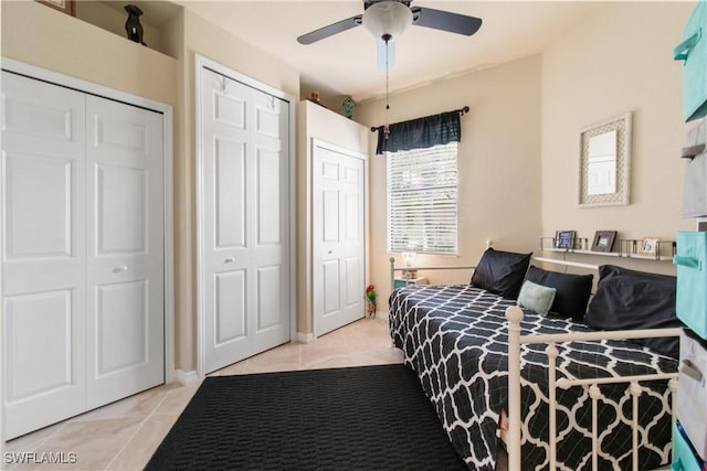 tiled bedroom with ceiling fan and two closets