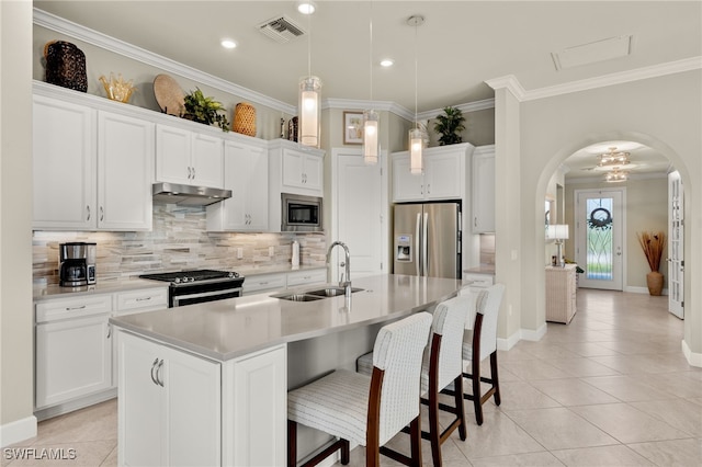 kitchen with appliances with stainless steel finishes, sink, pendant lighting, a center island with sink, and white cabinetry