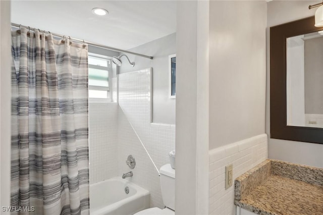 full bathroom featuring vanity, toilet, shower / bathtub combination with curtain, and tile walls