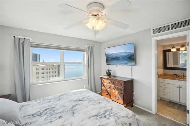 bedroom featuring ceiling fan, light colored carpet, and ensuite bathroom