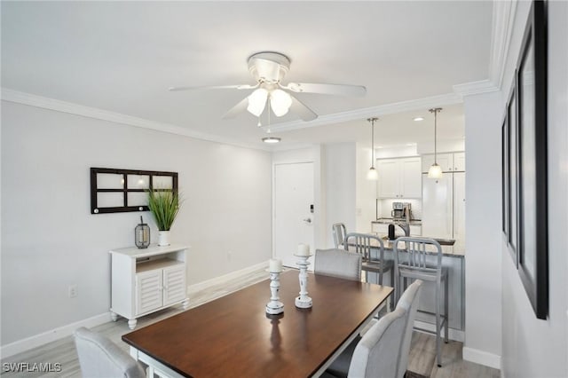 dining room with ceiling fan, crown molding, and light hardwood / wood-style flooring