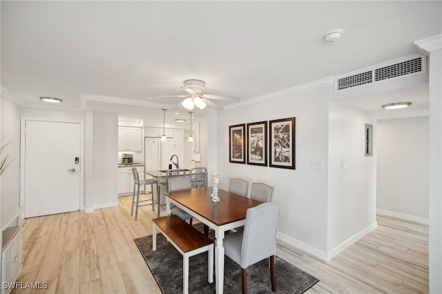 dining area featuring light wood-type flooring, ceiling fan, and crown molding