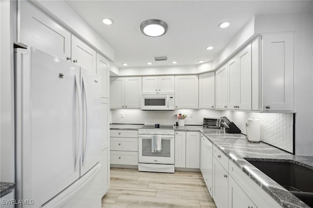 kitchen featuring white cabinets, light stone counters, white appliances, and tasteful backsplash