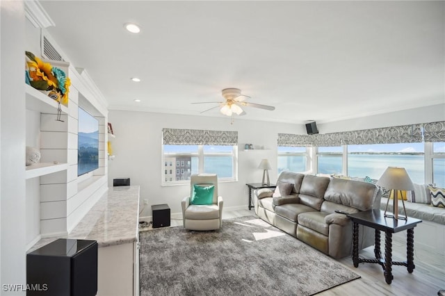 living room with ceiling fan, a water view, ornamental molding, and wood-type flooring