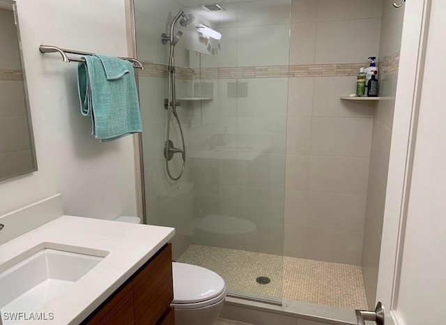 bathroom featuring vanity, toilet, and a tile shower