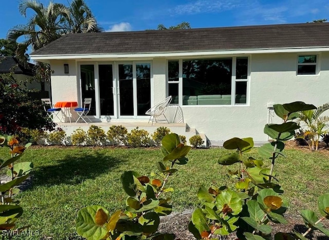 back of house with french doors and a lawn