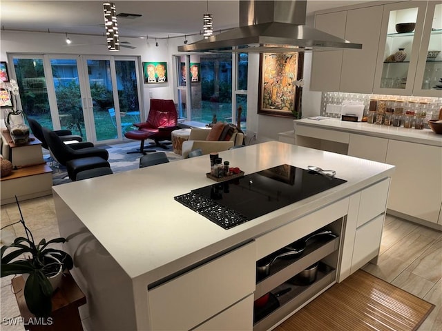 kitchen featuring a center island, exhaust hood, white cabinets, black electric cooktop, and wall oven