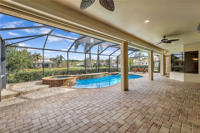 view of pool featuring glass enclosure, ceiling fan, a patio, and an in ground hot tub