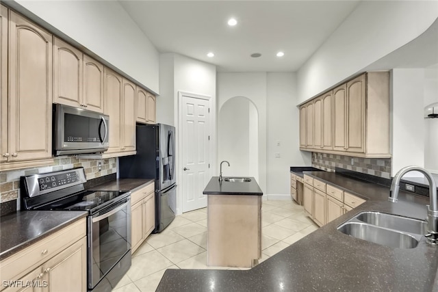 kitchen featuring a center island with sink, backsplash, sink, and appliances with stainless steel finishes