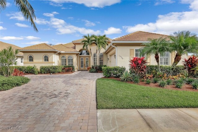 mediterranean / spanish-style home featuring a front lawn and a garage