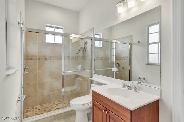 bathroom with tile patterned flooring, vanity, a shower with door, and toilet