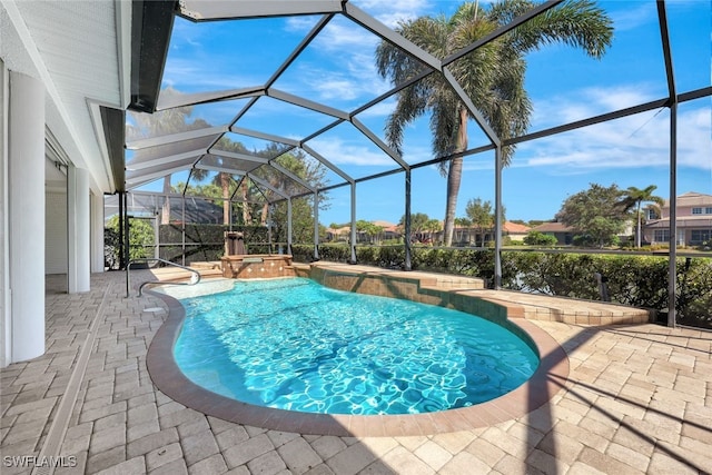 view of pool featuring glass enclosure, a pool with connected hot tub, and a patio area