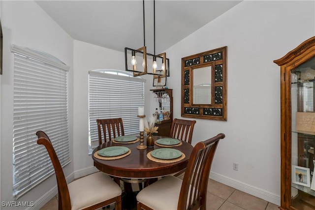 tiled dining space with vaulted ceiling and an inviting chandelier