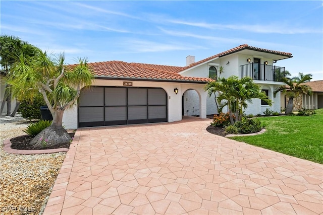 mediterranean / spanish house featuring a garage, a balcony, and a front lawn