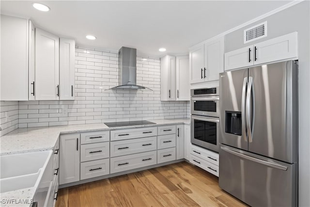 kitchen with backsplash, white cabinetry, wall chimney exhaust hood, and stainless steel appliances