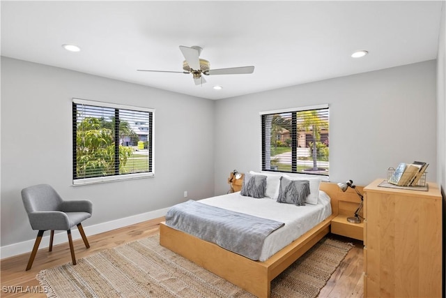 bedroom with multiple windows, light hardwood / wood-style flooring, and ceiling fan