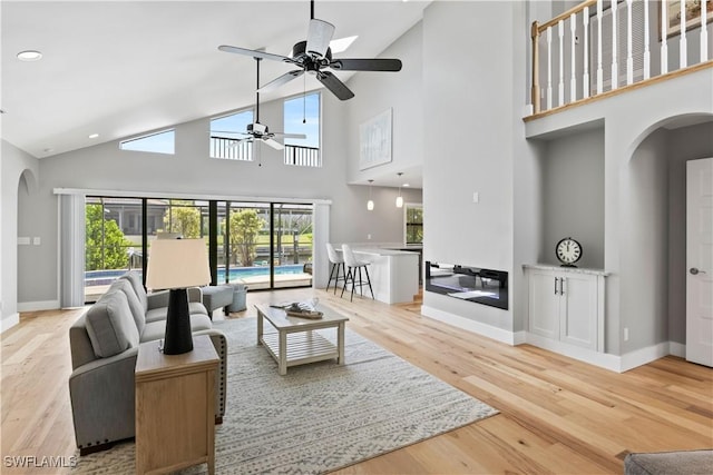 living room featuring ceiling fan, hardwood / wood-style floors, and high vaulted ceiling