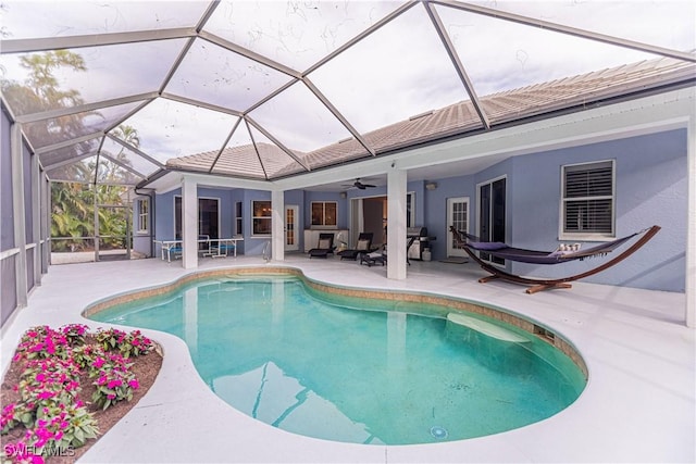 view of swimming pool with a patio, glass enclosure, and ceiling fan