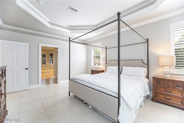 tiled bedroom featuring a raised ceiling, ornamental molding, and ensuite bath