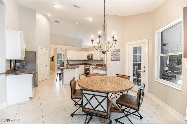 tiled dining room featuring a towering ceiling and a notable chandelier