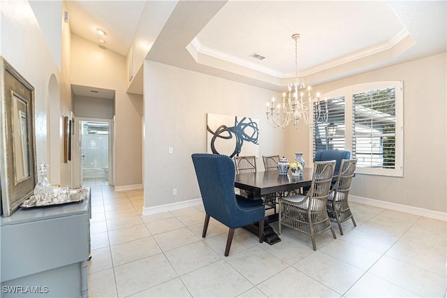 dining area with a raised ceiling, light tile patterned floors, and an inviting chandelier