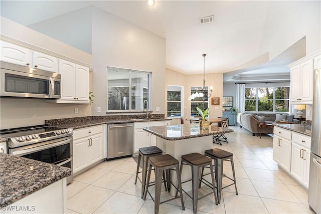 kitchen featuring appliances with stainless steel finishes, sink, pendant lighting, dark stone countertops, and a center island