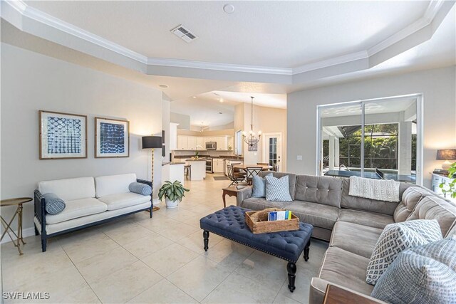 tiled living room with a raised ceiling, ornamental molding, and a chandelier