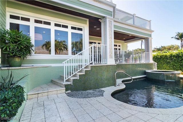 exterior space with a swimming pool with hot tub and a balcony