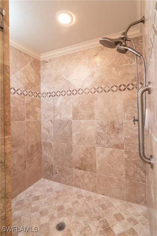 bathroom with crown molding and a tile shower